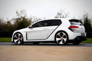 白色Volkswagen Golf GTI Concept在秋樹間的道路上奔馳。 — 福斯汽車 壁紙
