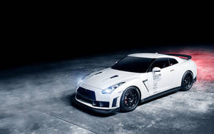 白色日產GT-R賽車，帶有黑色車輪和發光車頭燈，停在深色混凝土地板上。 — 日產 壁紙
