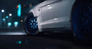 霓虹燈下，夜晚潮濕的城市街道上的白色汽車，藍色車輪。 — 野馬GIF 壁紙