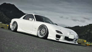 白色馬自達RX-7跑車停泊在山路上，背景為陰天天空。 — 馬自達 壁紙