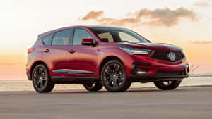 紅色Acura SUV在日落時停泊在海邊，金色光線反射在表面上。 — Acura 壁紙