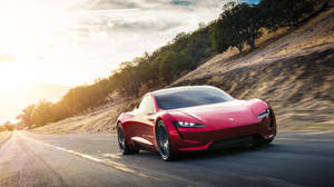 紅色Tesla Roadster在日落時分在風景優美的山路上疾馳。 — 極高畫質 壁紙