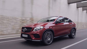 紅色梅賽德斯 GLE Coupe 在帶有模糊混凝土牆壁的城市道路上行駛。 — Mercedes Benz C300 壁紙