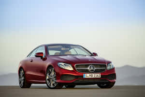 紅色梅賽德斯E級轎跑車停在開闊的道路上，背景有山巒。 — Mercedes Benz C300 壁紙