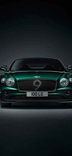 在攝影棚燈光下，深色背景中的綠色 Bentley 豪華車。 — Galaxy S26 壁紙