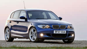 藍色BMW 1系列在暮色中停在礫石上，車頭燈亮著。 — Mercedes Benz C300 壁紙