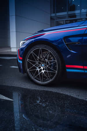 帶有賽車條紋的藍色BMW M4夜間停在濕漉漉的路面上。 — Huawei MatePad 壁紙