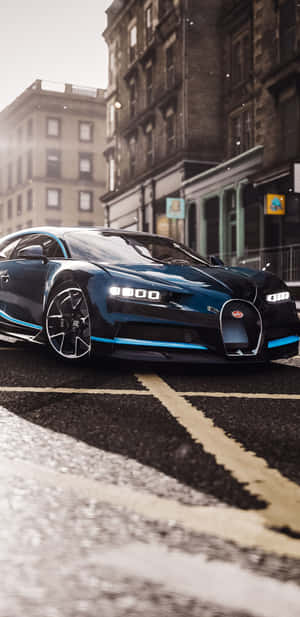 一輛藍色Bugatti Chiron停泊在濕漉漉的城市街道上，背景是歷史建築。 — Pixel 4 壁紙