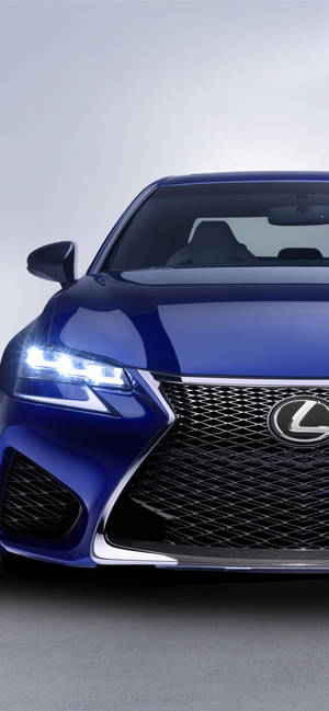 藍色Lexus車頭特寫，頭燈在工作室環境中亮起。 — iPhone 15 Pro Max 壁紙