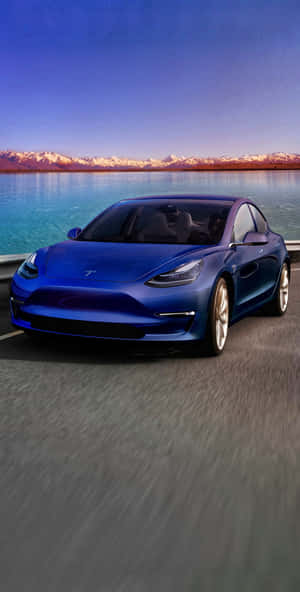 藍色Tesla Model 3在日落時分行駛在海岸公路上，背景有山脈和水。 — 蘋果標誌 iPhone 壁紙
