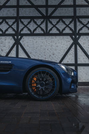 藍色跑車帶橙色煞車，停放在濕漉漉的路面上，靠近裝飾牆。 — Mercedes Benz C300 壁紙