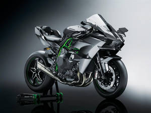 展示中的銀綠色Kawasaki運動摩托車，帶有反射表面。 — 黑色 壁紙