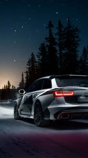 銀色 Audi 旅行車在夜間星空下行駛在雪路上穿越森林。 — 奧迪 GIF 壁紙