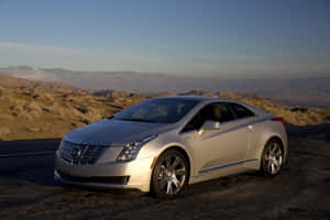 日落時分停在沙漠公路上的銀色 Cadillac ELR 電動雙門跑車。 — Surface Laptop 壁紙