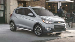 銀色 Chevrolet Spark 停放在咖啡館附近的人行道上，有人群。 — Vans 標誌 壁紙