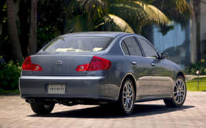 銀色 Infiniti G35 轎車停放在磚砌車道上，旁邊有棕櫚樹。 — Steam Deck OLED 壁紙