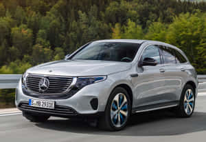 銀色 Mercedes-Benz EQC 電動 SUV 在森林道路上行駛。 — Surface Laptop 壁紙