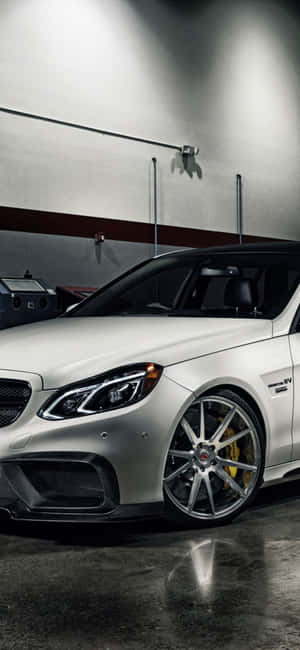 車庫中的銀色 Mercedes-AMG 跑車，配備金色制動器。 — Pixel 10 Pro XL 壁紙