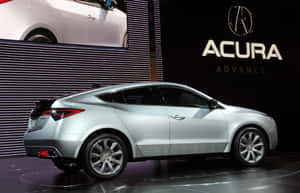 銀色Acura轎跑車在車展上展示，背後有品牌標誌。 — Acura 壁紙