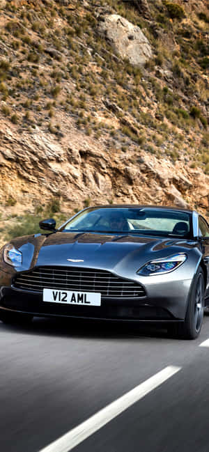 銀色Aston Martin在日落時分的山路上疾馳 — OnePlus 13 壁紙