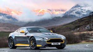 銀色Aston Martin跑車帶黃色飾邊，停在夕陽下的山路上。 — 奧斯頓馬丁 壁紙