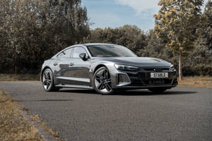 銀色Audi e-tron GT電動車停放在秋季林蔭大道上。 — 奧迪 GIF 壁紙