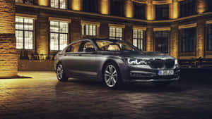 銀色BMW 7系列轎車在夜間停泊在燈光明亮的磚造建築前。 — Mercedes Benz C300 壁紙