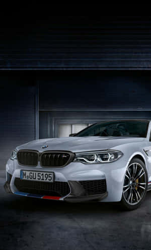 銀色BMW M5跑車停放在黑暗的工業車庫中。 — Tecno Megapad 壁紙