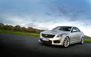 銀色Cadillac CTS-V轎車停放在黃昏的路上，背景有秋葉。 — 凱迪拉克 壁紙