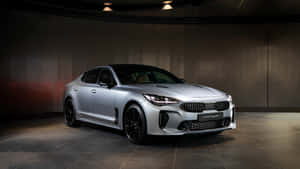 銀色Kia Stinger跑車在昏暗的工作室中，帶有聚光燈效果。 — 起亞 壁紙
