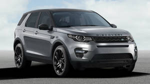 銀色Land Rover Discovery SUV停放在灰色路面，天空多雲。 — 1600x900 壁紙