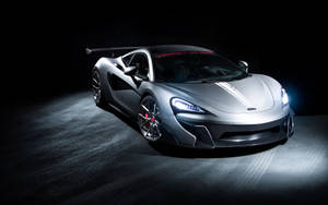 銀色McLaren跑車在黑暗的攝影棚燈光下帶有發光的車頭燈。 — 麥拉倫 壁紙