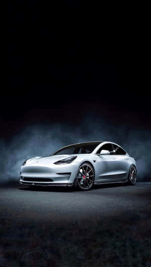 銀色Tesla Model 3在深色煙霧背景上被聚光燈照亮。 — 酷炫iPhone 壁紙