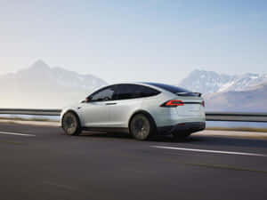 銀色Tesla Model X在高速公路上行駛，背景有雪山 — 特斯拉 壁紙
