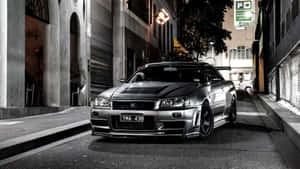 銀色日產Skyline R34在夜間停放在狹窄的城市小巷中。 — 霓虹車 壁紙
