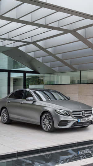 銀色梅賽德斯-奔馳轎車停放在現代玻璃天篷下，帶有水倒影。 — Mercedes-Benz 壁紙