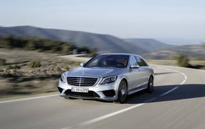 銀色梅賽德斯轎車在日落時分行駛在蜿蜒的山路上。 — Mercedes Benz C300 壁紙