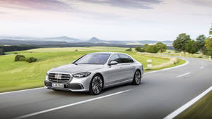 日落時分，銀色豪華轎車在風景如畫的鄉村道路上行駛。 — Mercedes-Benz 壁紙
