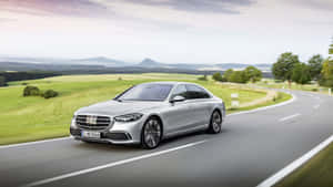 銀色豪華轎車在風景如畫的鄉村道路上行駛。 — Mercedes-Benz 壁紙