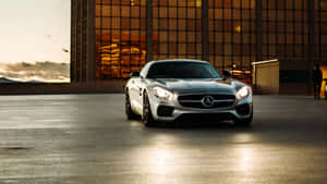 銀色跑車停放在玻璃建築前，夕陽時分。 — Mercedes Benz C300 壁紙