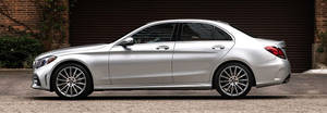銀色賓士轎車停放在磚牆和車庫門附近的碎石上。 — Mercedes Benz C300 壁紙