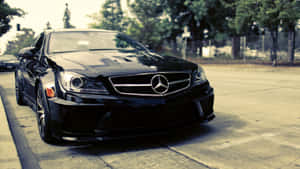黑色 Mercedes-Benz 跑車停泊在陽光明媚的城市街道上。 — Mercedes Benz C300 壁紙