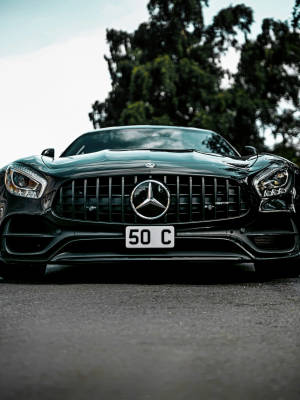 黑色 Mercedes-AMG GT 跑車停泊在戶外，後面有樹木。 — 超跑 壁紙