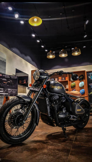黑色 Royal Enfield 摩托車在現代室內展廳中展示，配有溫暖的照明和木架。 — 巴布風機車 壁紙