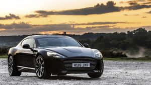金色夕陽下碎石地上的黑色Aston Martin DB9。 — 奧斯頓馬丁 壁紙