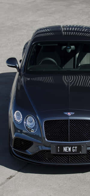 黑色Bentley New GT跑車在明亮陽光下停放在混凝土上。 — iPhone 14 Pro Max 壁紙
