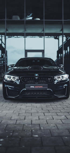 黑色BMW M4跑車停放在現代玻璃牆車庫的磚地上。 — Pixel 10 Pro 壁紙