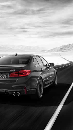 黑色BMW M5在沙漠公路上疾馳，背景有山。 — Mercedes Benz C300 壁紙