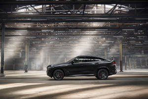 黑色BMW X6 M在廢棄倉庫中，陽光穿過橫樑照射。 — Mercedes Benz C300 壁紙