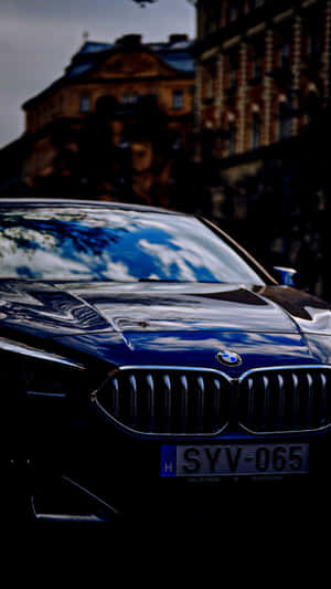黑色BMW汽車，帶有天空和雲朵的倒影，停放在歷史建築附近。 — 昏暗 壁紙